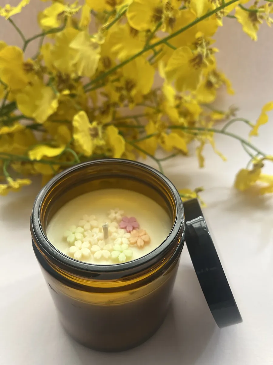 Cozy Spice candle in an amber glass jar topped with small wax flowers