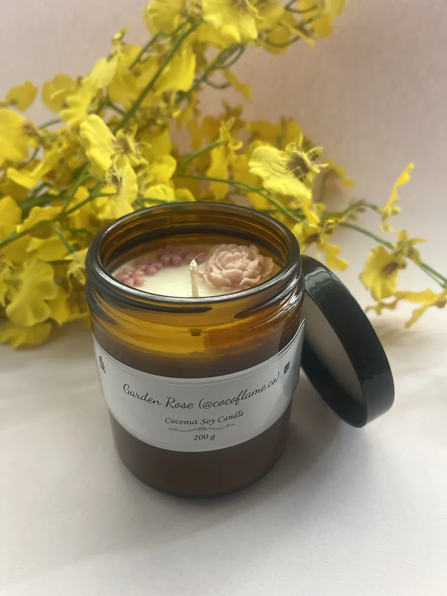 Garden Rose candle in an amber glass jar with a pink wax rose